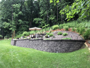 Outdoor living area carved out of a steep slope with retaining walls and custom block steps